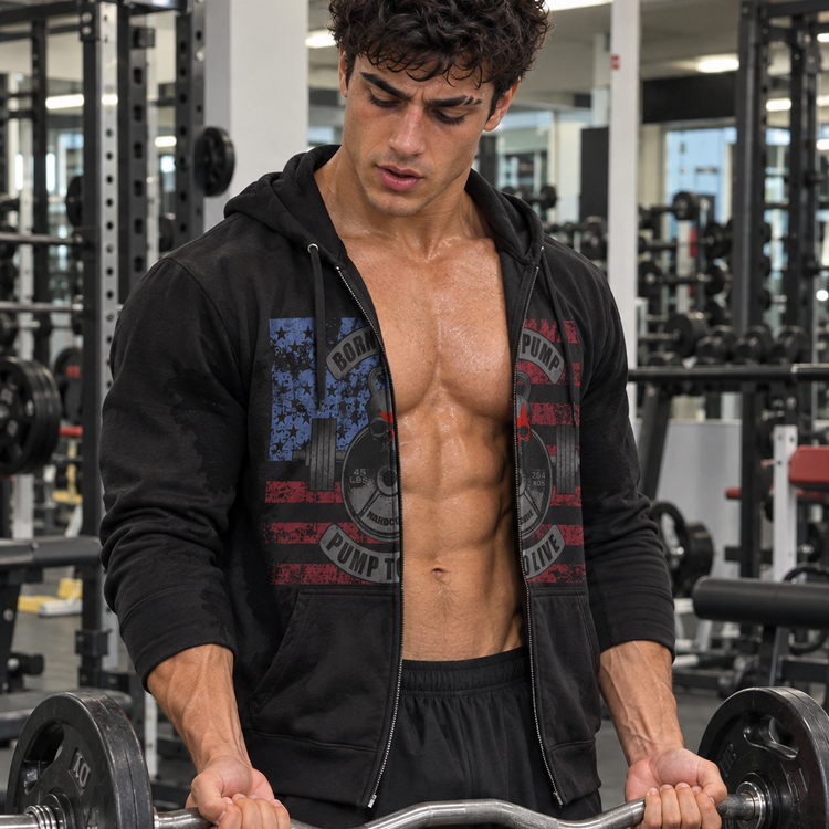 A muscular man in a gym setting, wearing a black zip-up Gymstar hoodie with a red and blue graphic print on the front, black athletic shorts, and lifting a barbell.