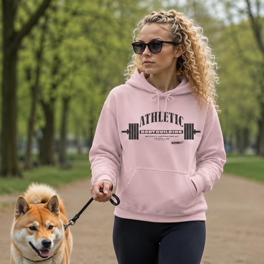 Woman walking a dog in a park wearing a pink Gymstar hoodie with 'Athletic' text.