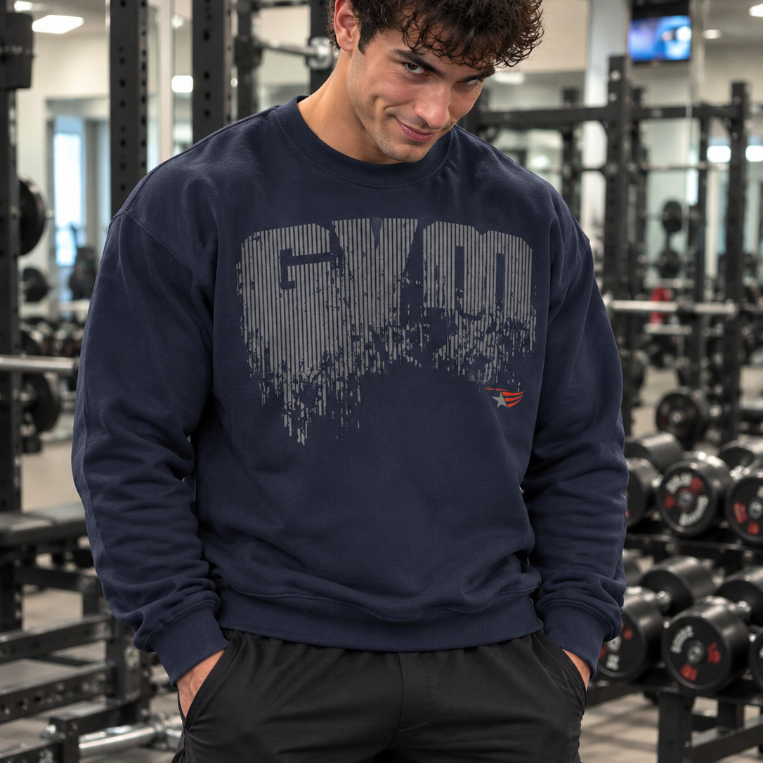 Luca Moretti wearing a navy blue GYMSTAR crewneck sweatshirt with a distressed GYM graphic print, smiling at the camera with his hands in his pockets in a gym.