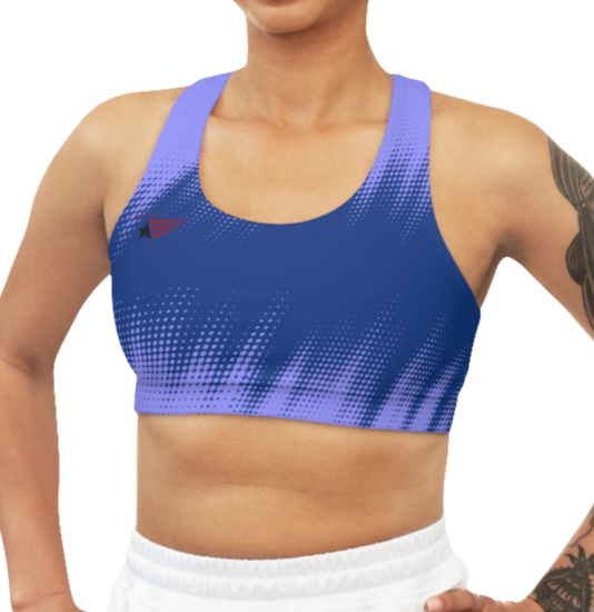 A women's athletic sports bra. It is primarily blue with a bright blue, dotted, gradient pattern that radiates from the sides and bottom. The straps are solid red. A small logo featuring a star and three red and blue stripes is on the left side of the chest.