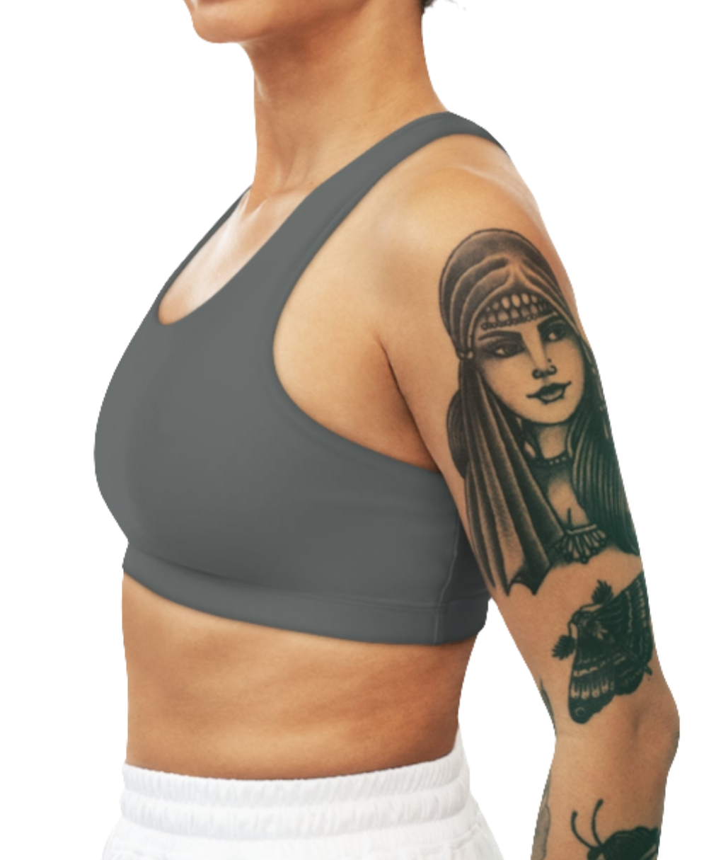 
A women's solid gray athletic sports bra Gymsatr, shown from the side. It has a scoop neckline and a racerback style. The sports bra is worn by a person with tattoos on their upper arm.