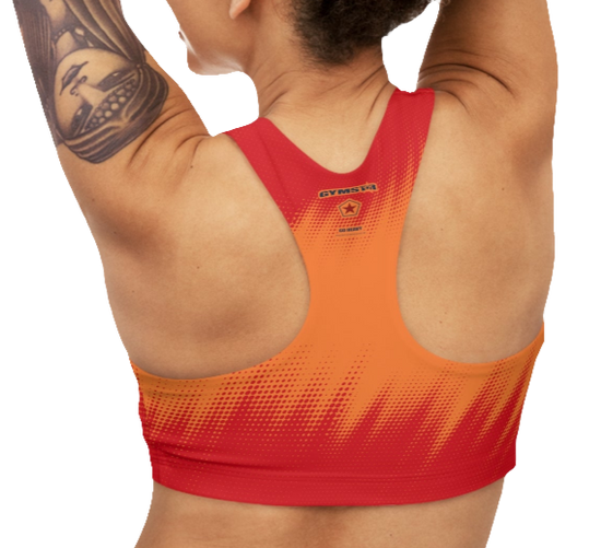 A women's athletic sports bra Gymstar, shown from the back. It features a red and orange color scheme with a dotted, gradient pattern radiating from the bottom. The straps are solid red and form a racerback style. The brand's logo, a red star within a circle of smaller stars, is printed on the upper back, along with the "GYMSTAR" brand name.