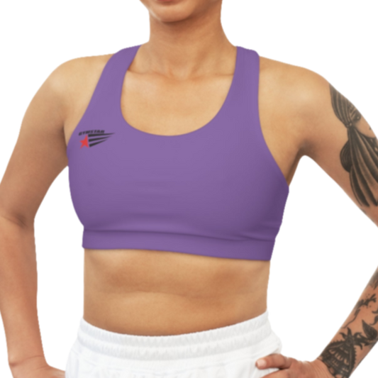 A woman wearing purple athletic sports bra, shown from the front. The straps are solid  and form a racerback style at the back. A small logo featuring a star and three red and blue stripes is on the left side of the chest.