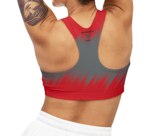 A women wearing athletic sports bra, shown from the back. The main body is gray with a red, dotted, gradient pattern that radiates from the bottom. The straps are solid red and form a racerback style. The brand name "GYMSTAR" and a logo are visible on the back, between the shoulder blades.