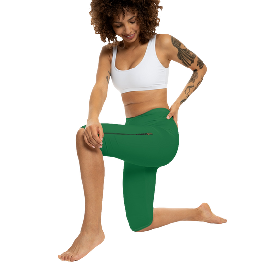 A woman wearing green high-waisted fitness leggings Gymstar with a logo on the waistband, paired with white sneakers. Action front view.