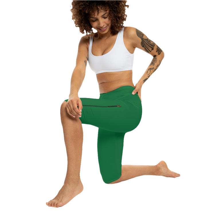 A woman wearing green high-waisted fitness leggings Gymstar with a logo on the waistband, paired with white sneakers. Action front view.