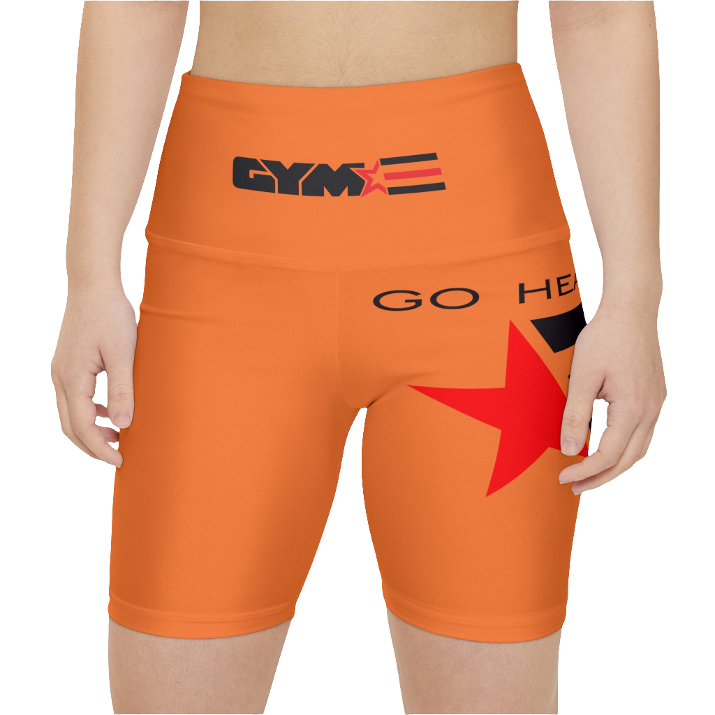 A woman wearings pair of orange Gymstar women's workout leggings with 'GYMSTAR' and 'GO HEAVY' text, along with a star graphic, on a person mid-section view. front close up view.