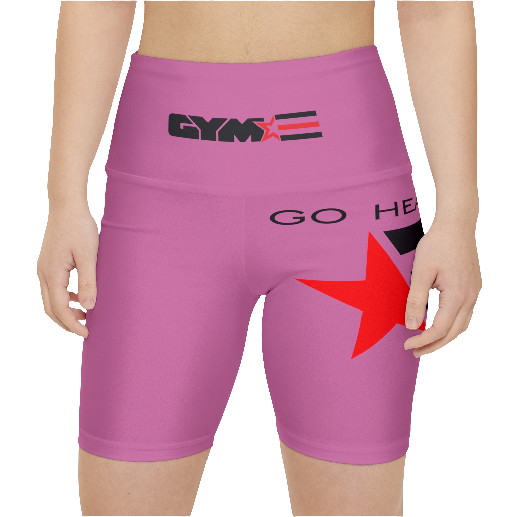 A womanwearings pair of pink women's workout leggings with a logo on the left thigh and the text 'GO HEAVY' on the right thigh. The leggings are designed to be skinny fit and have a mid-rise waist. Front close up view.
