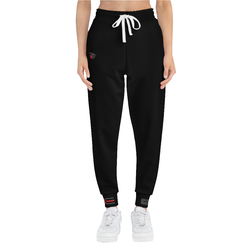 A person standing frontal, wearing black joggers Gymstar with a logoand white sneakers. The joggers have a ribbed bottom and waistband cuffs, and feature two side pockets.