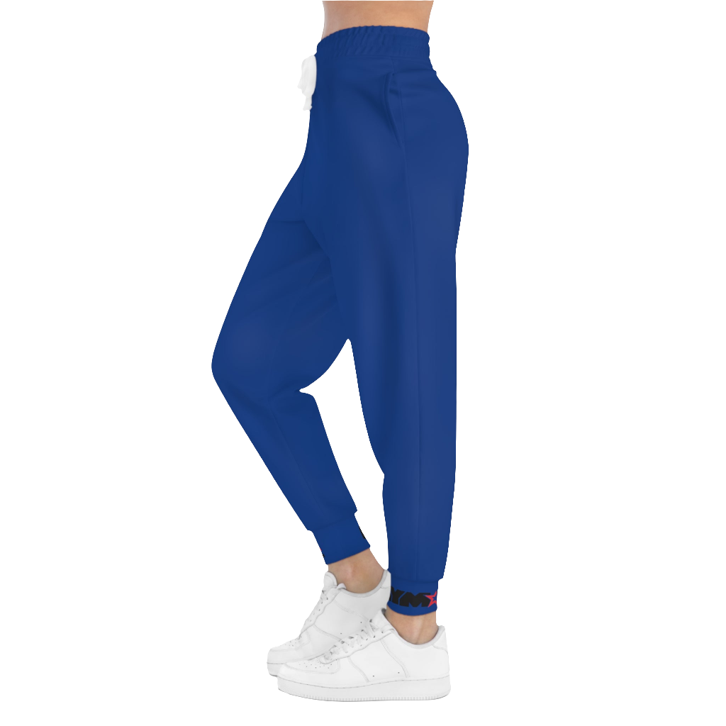 A woman wearing blue sports joggers with an elastic waistband and drawstrings, featuring a logo on the left leg and a white sneaker left side view.
