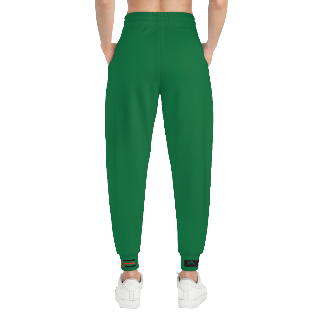A woman wearing green sports joggers with an elastic waistband and drawstrings, featuring a logo on the left leg and a white sneaker back side view.