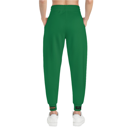 A woman wearing green sports joggers with an elastic waistband and drawstrings, featuring a logo on the left leg and a white sneaker back side view.