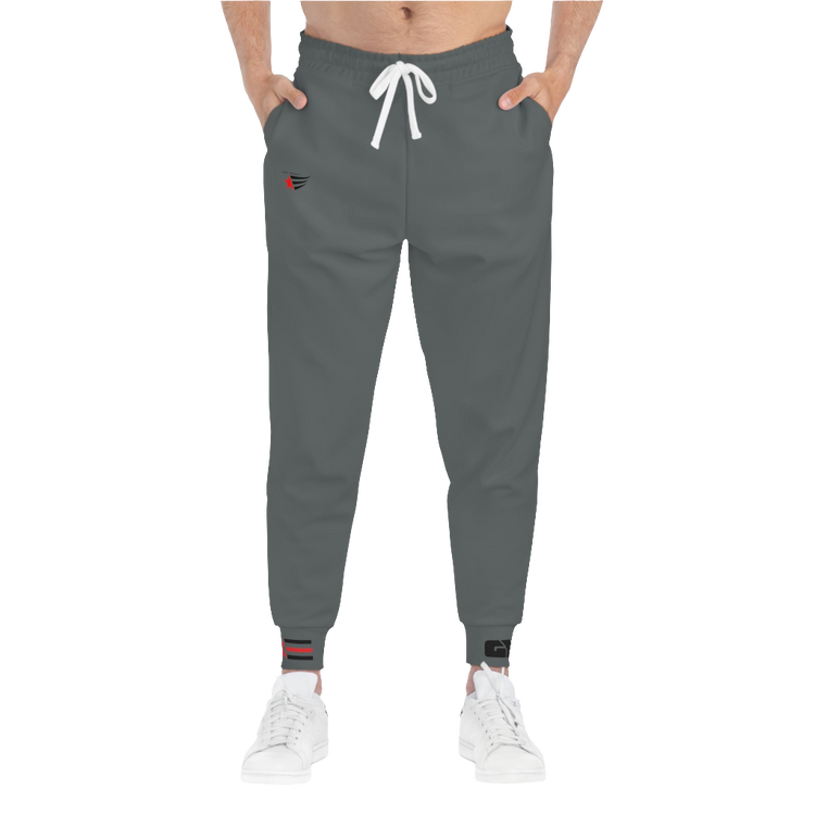 A person standing frontal, wearing silver gray joggers Gymstar with a logoand white sneakers. The joggers have a ribbed bottom and waistband cuffs, and feature two side pockets.