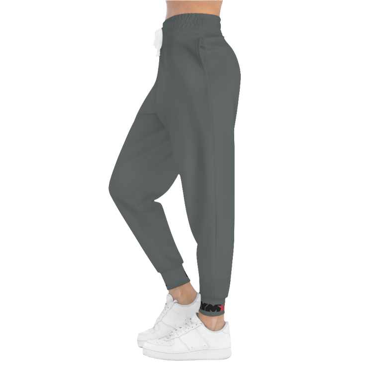 A person standing frontal, wearing silver gray joggers Gymstar with a logoand white sneakers. The joggers have a ribbed bottom and waistband cuffs, and feature two side pockets.