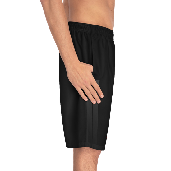 A man wearing black sports shorts with an elastic waistband and drawstrings, featuring a logo on the left leg  left side view.