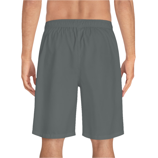 A man wearing grey sports shorts with an elastic waistband and drawstrings, featuring a logo on the left leg  back side view.