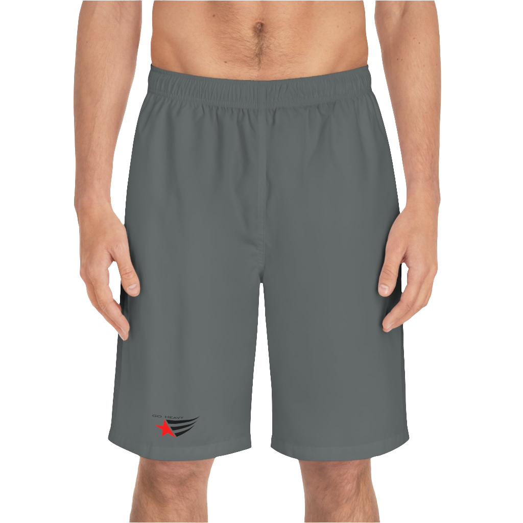 A man wearing grey sports shorts with an elastic waistband and drawstrings, featuring a logo on the left leg  front side view.