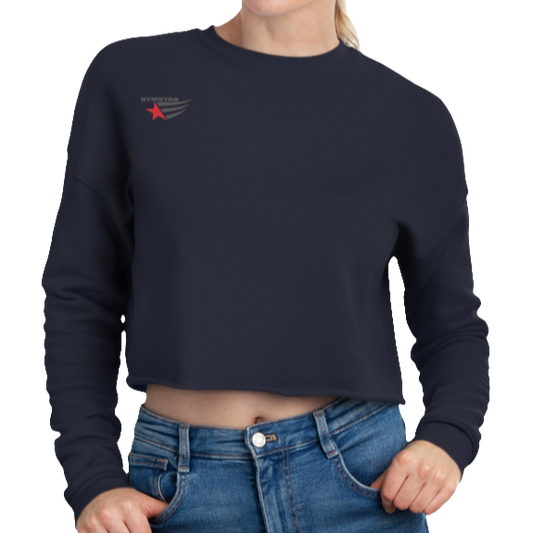A woman wearing a navy blue cropped Gymstar sweatshirt with a logo on the chest and a graphic on the left sleeve, paired with blue jeans.