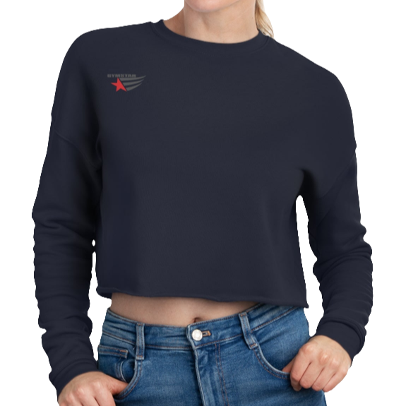 A woman wearing a navy blue cropped Gymstar sweatshirt with a logo on the chest and a graphic on the left sleeve, paired with blue jeans.